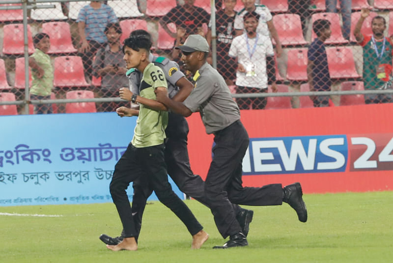 বাংলাদেশ–অস্ট্রেলিয়া ম্যাচ চলাকালে মাঠে ঢোকা এক দর্শককে বের করে দিচ্ছেন নিরাপত্তাকর্মীরা